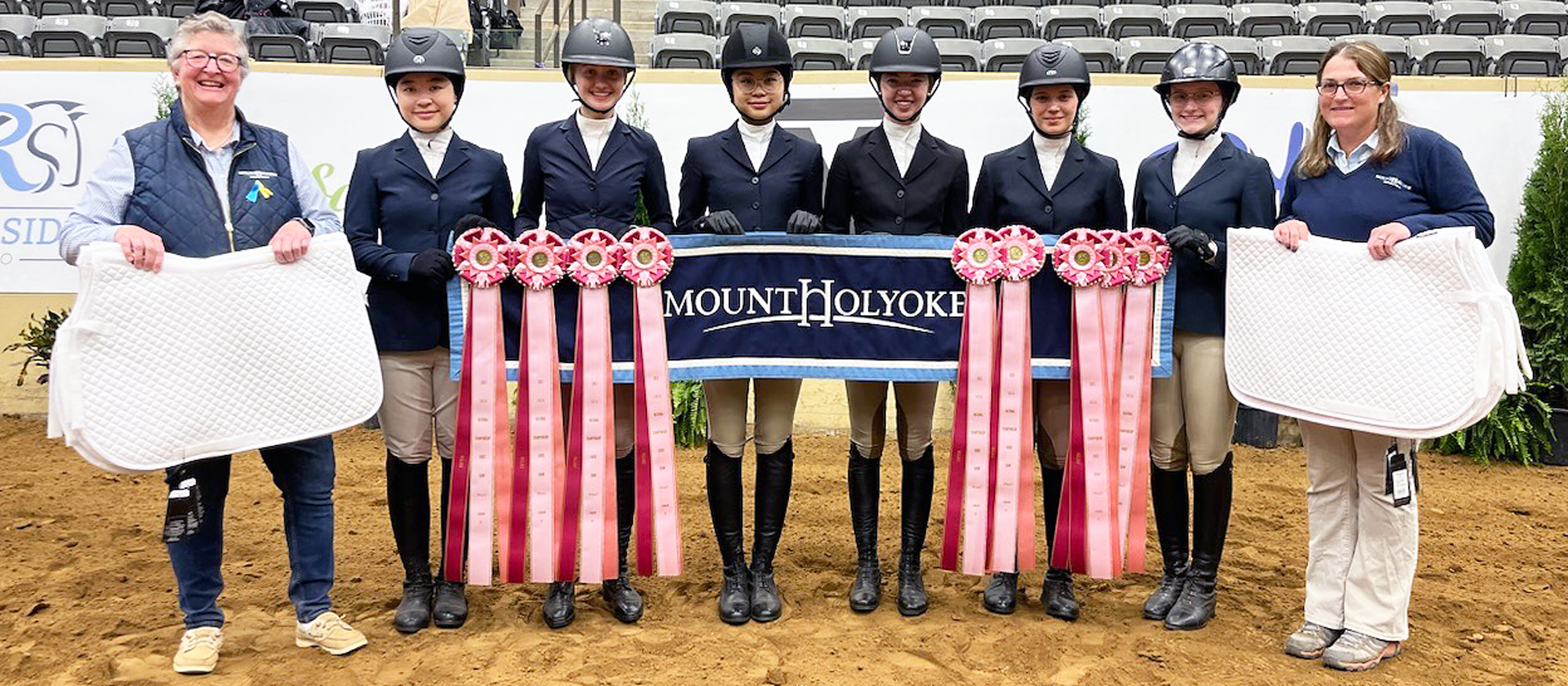 Posing after their fifth-place national finish from the Mount Holyoke hunter seat riding team, from left to right: head coach CJ Law, Lingdang Zhang, Helena Weiss, Kerina Li, Emmie Mirarchi, Em Cantalupo, Cate Bates, and assistant coach Morgan Lynch.