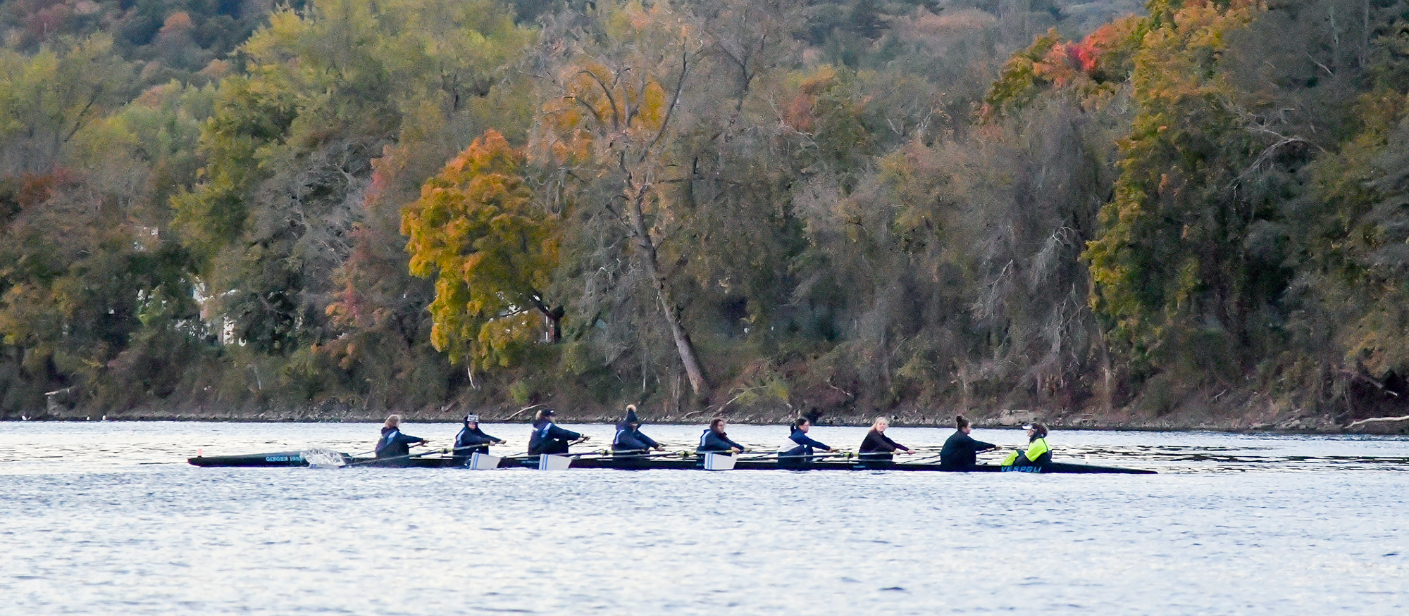 Action photo of the Lyons rowing team on the water of the Connecticut River.