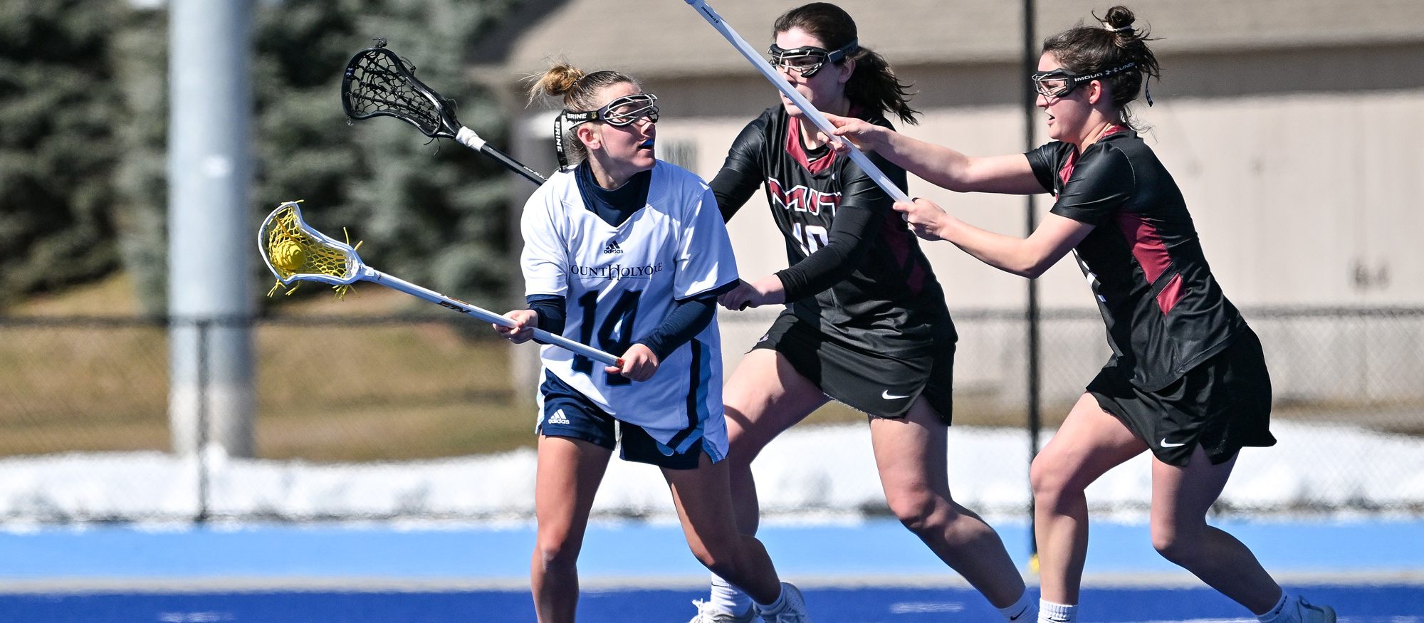 Mount Holyoke first-year midfielder Emi Bisson faces double coverage against MIT's defense in the Lyons' NEWMAC opener on March 18, 2023. (Bob Blanchard/RJB Sports)