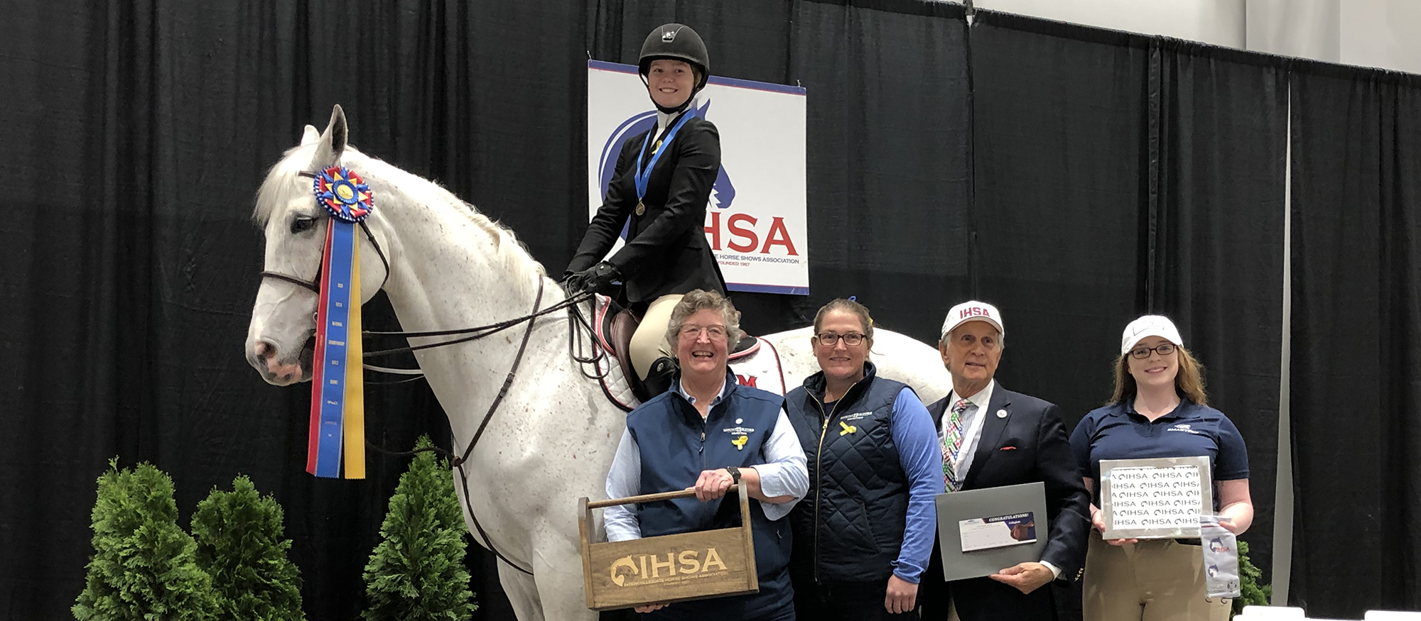 Sophomore Sara Hearn in the winner's circle with Head Coach CJ Law, Assistant Coach Morgan Lynch, IHSA President Bob Cacchione and an attendant after winning the Individual Intermediate Over Fences National Championship on May 2, 2019.